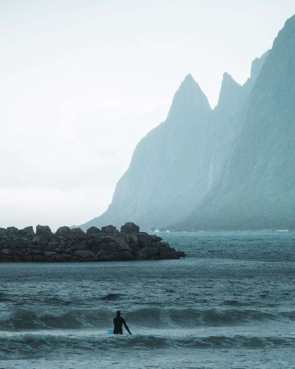 Surfer i vannet foran de dramatiske Segla-toppene