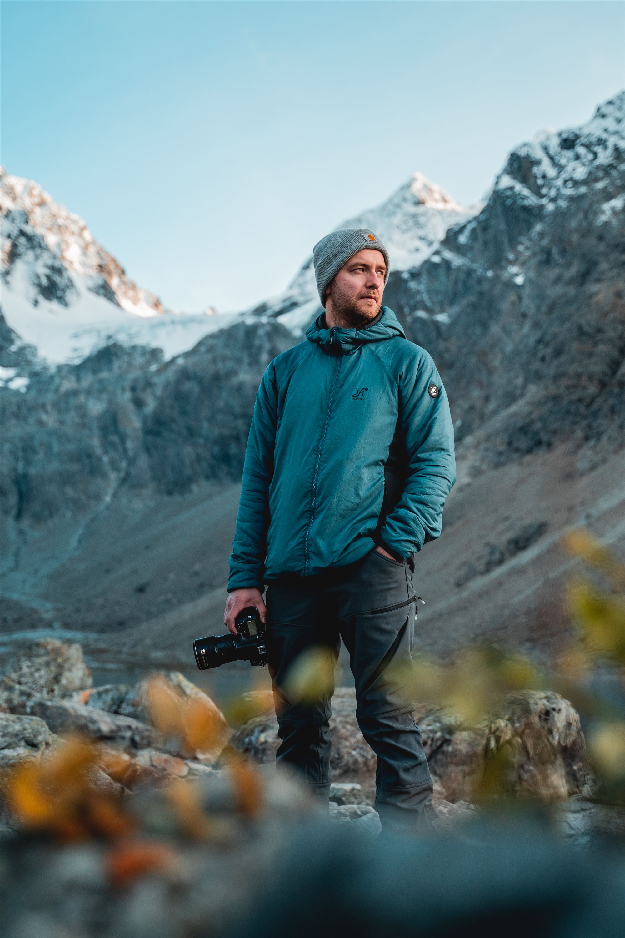 Thomas Berg Rasmussen med kamera i hånden foran snødekte fjell